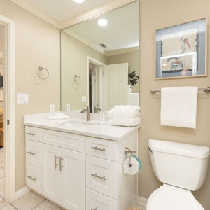 Fresh towels lie ready on the bathroom counter while seashell curtains hint at coastal charm nearby