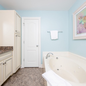 Luminous master bathroom featuring a jetted tub, walk-in shower, granite countertops, and a colorful sea turtle artwork