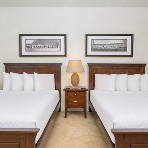 The guest bedroom features two beds, elegant wood furnishings, and stylish artwork, creating a serene retreat for relaxation