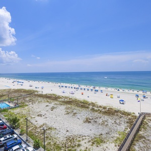This stunning view showcases the beach, with vibrant umbrellas dotting the white sand and a glimpse of the sparkling water