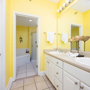 The bright master bathroom features a double vanity with white cabinetry, a relaxing soaking tub, and a spacious shower