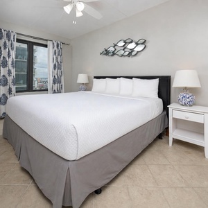 The master bedroom features a comfortable king bed, stylish decor, and a lovely view through large windows