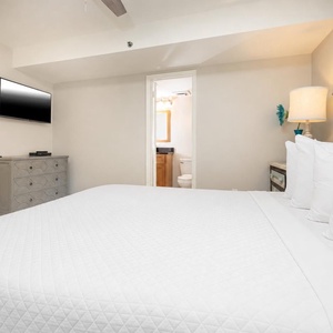 This cozy bedroom features a large king bed, a mounted TV, and an inviting atmosphere with soft lighting