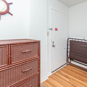 This entryway features a stylish wicker dresser and a convenient foldable bed, perfect for additional guests
