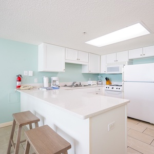 Prepare meals in this kitchen, featuring a breakfast bar with stools and essential appliances for your convenience