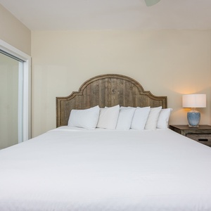 Guest bedroom featuring a plush king bed, decorative wooden headboard, and soft lighting from a stylish bedside lamp