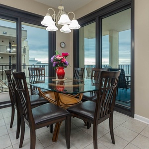 Dining area features a glass table surrounded by dark wood chairs, with a vibrant floral centerpiece