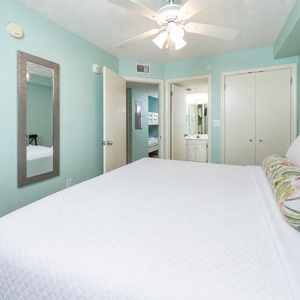 Serene bedroom with a plush king bed, soothing teal walls, TV, and en-suite bathroom