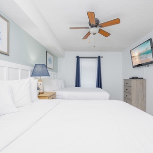 Unwind in this inviting guest bedroom with two queen beds, coastal decor, and a TV