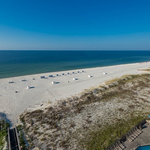 Enjoy the expansive view of the beach and water, with lounge chairs inviting you to relax under the sun