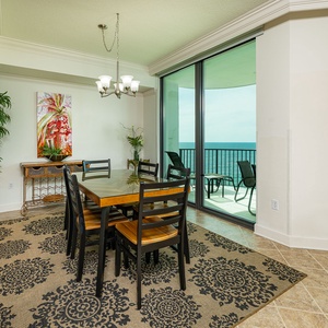 Dine in style at the round table with plush chairs, surrounded by vibrant decor and expansive views through large windows
