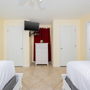 Cozy guest bedroom featuring two double beds, a TV, and easy access to the adjoining bathroom