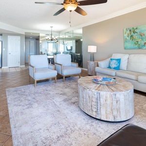 Unwind in the inviting living area with stylish seating, a round coffee table, and vibrant coastal decor
