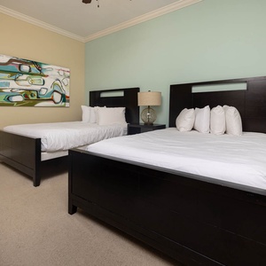 This guest bedroom features two stylish full beds, a colorful abstract painting, and a warm, inviting atmosphere