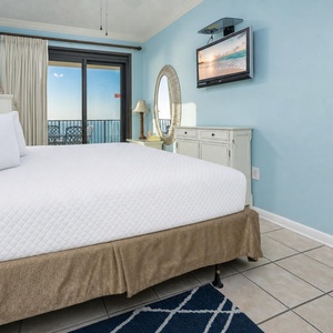 Bright blue walls complement the inviting king bed in the master, while a balcony view showcases the beach