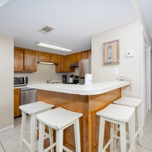 The kitchen features warm wooden cabinetry, a breakfast bar with seating, and convenient appliances for meal prep