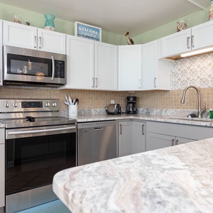 Open kitchen design featuring stainless appliances, elegant marble countertops, and coastal decor accents