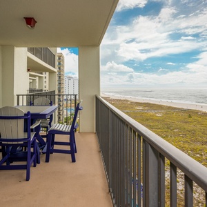 Balcony seating with a blue table and chairs offers a serene view of the beach and gulf, perfect for relaxation