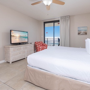 Cozy master suite featuring a large king bed, vibrant chair, and a view that invites the beach into your room