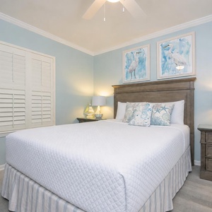 Quiet moments await in the guest suite with a queen bed framed by calming coastal artwork and gentle lighting