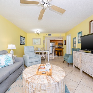 Living area featuring a gray sofa with decorative pillows, a round wooden coffee table, and a flat-screen TV