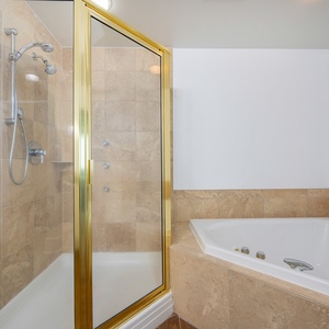 Relax in this elegant master bath featuring a luxurious jetted tub and a spacious walk-in shower with stylish gold accents