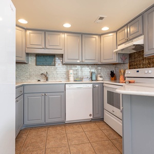 Kitchen featuring light gray cabinetry, white appliances, and a charming beach wall sign