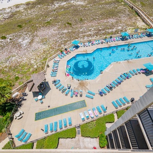 Aerial view showcases the pool area with vibrant loungers, a shaded gazebo, and guests enjoying the refreshing water