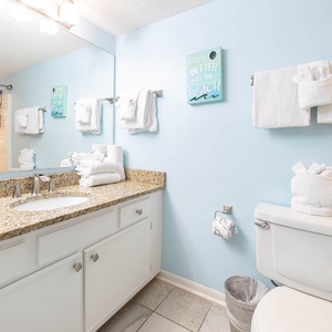 Bright guest bathroom featuring a granite countertop, fresh towels, and a tub/shower combo for a refreshing experience