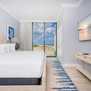 Serene king guest suite with large windows showcasing beautiful coastline views
