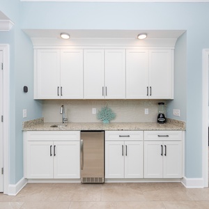 Enjoy preparing drinks in the wet bar with granite countertops and coastal decor