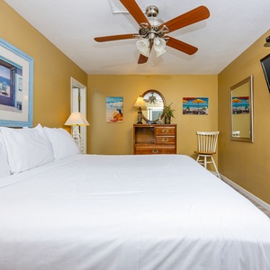 This cozy guest bedroom features a large bed, a mounted TV, and charming beach-themed decor for a relaxing stay