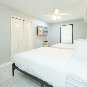 The guest room features two twin beds, a cozy atmosphere with a TV on a dresser, a mirror, and a storage bench