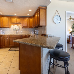 Cook and gather in the kitchen featuring rich wood cabinetry, granite countertops, and seating at the bar