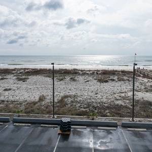 This inviting view showcases a serene beachfront, perfect for relaxation, with a glimpse of the boardwalk in the distance