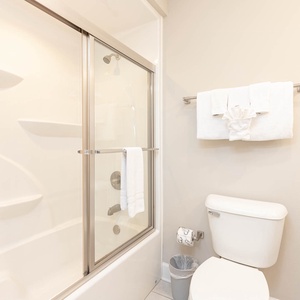 Indulge in a refreshing shower in this guest bath, surrounded by luxurious towels and soothing light