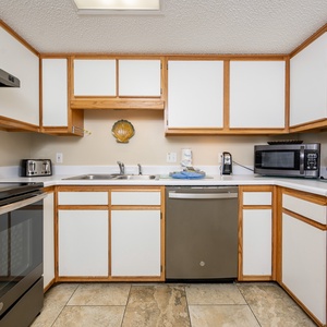 The fully-equipped kitchen features light wood cabinetry, a sleek black stove, and a coffee maker for your convenience