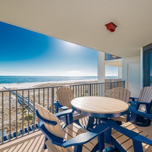 Balcony with a round table and adirondack chairs offers a direct view of the beach and the sparkling gulf waters