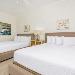 Cheerful guest bedroom featuring two cozy queen beds and charming nautical artwork for a relaxing retreat