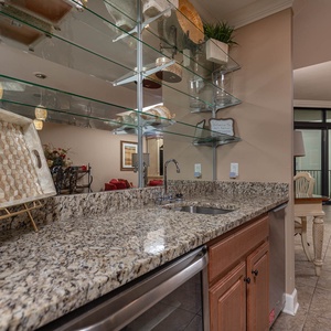 The wet bar features elegant granite countertops, a wine cooler and glassware, and a view of the inviting living area