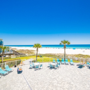 Bask in the sun on the pool-area patio with a vibrant beachfront view, perfect for relaxation and fun gatherings
