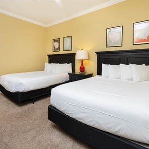 Comforting guest bedroom featuring two queen beds, stylish decor, and warm yellow walls for a cozy retreat