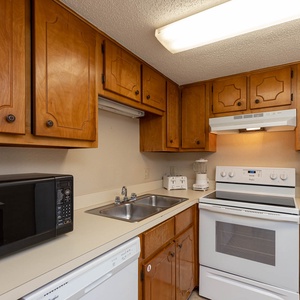This kitchen features warm wood cabinetry, essential appliances, and ample counter space for meal preparation