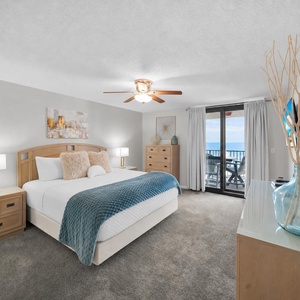 Master bedroom featuring a plush king bed, stylish decor, and a balcony with a view of the tranquil gulf waters