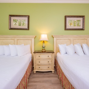 Drift into restful slumber on two queen beds with cozy pillows, surrounded by a refreshing coastal vibe in this guest room
