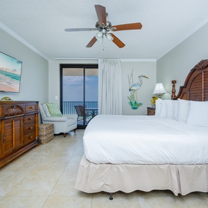 Relax in this inviting master suite featuring a king bed, coastal decor, and a balcony with beachfront access