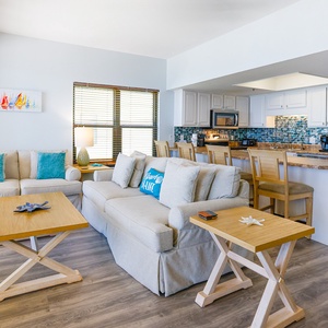 Bright living area featuring cozy seating, vibrant decor, and a modern kitchen with stainless appliances