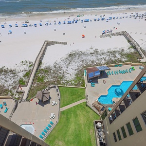 Relax with a view of the serene beach, vibrant umbrellas, and a sparkling pool from a spacious balcony