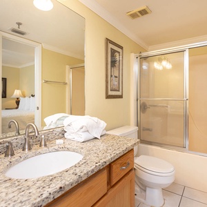 Bright bathroom featuring a granite countertop, a tub/shower combo, and fresh towels neatly arranged
