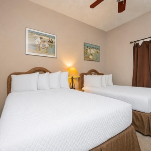 Experience restful nights in this cozy guest bedroom with two comfortable double beds, soft lighting, and charming artwork